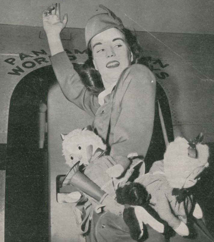 1952 Pan Am Stewardess boards an aircraft with charity toys for children at one of her ports of call.